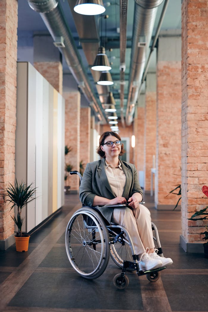 Confident businesswoman smiling while sitting in a wheelchair in a contemporary office setting.